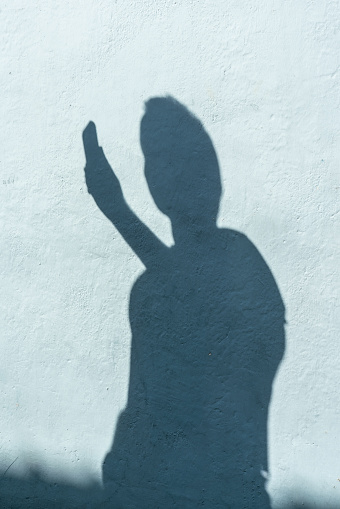 Shadow on wall of a man using a mobile. Vertical shot with copy space