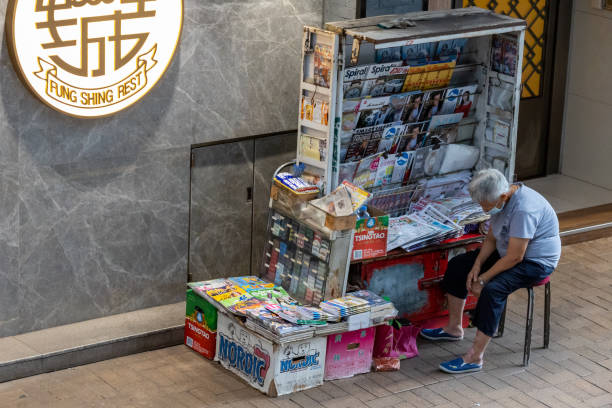 News stand in Causeway Bay, Hong Kong Hong Kong - September 22, 2021 : News vendor wearing face mask at the news stand in Causeway Bay, Hong Kong. Many newspapers, magazines, books and cigarettes are on sell at the news stand. newspaper seller stock pictures, royalty-free photos & images