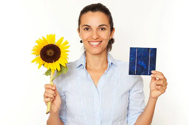 Pretty woman shows a solar cell and a sunflower