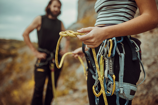 Couple is putting on climbing equipment,tying knots for safety harness and preparing for rock climbing