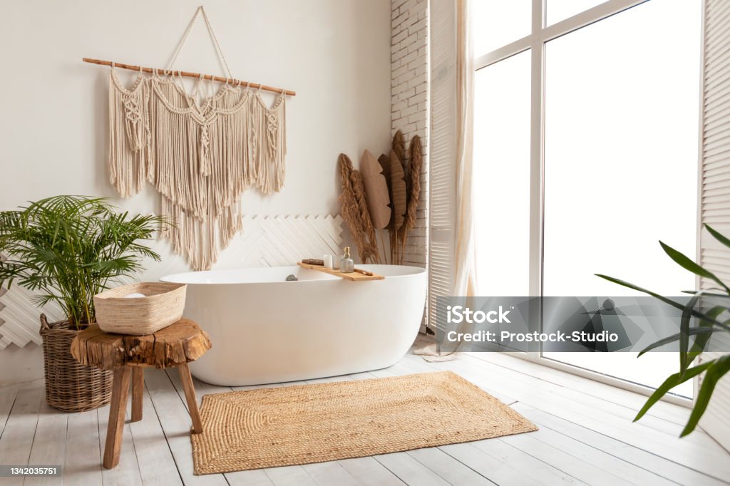 Cozy Empty Modern Bathroom Background With White Bathtub And Window Bathing Room Interior Design. Cozy Empty Modern Bathroom Background With White Bathtub And Panoramic Windows, Rustic Decorations And Green Plants Indoors Bathroom Stock Photo