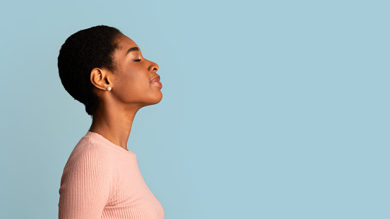 Profile Portrait Of Young African American Woman Standing With Closed Eyes Over Blue Background, Side View Shot Of Pleased Smiling Beautiful Black Posing In Studio, Panorama With Copy Space