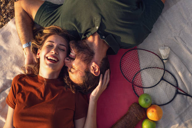 giovane coppia felice, sdraiata sulla coperta da picnic, che condivide l'affetto l'uno con l'altro, celebra il loro amore - couple affectionate relaxation high angle view foto e immagini stock