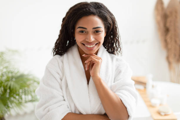 istock Black Lady Posing Wearing White Bathrobe Touching Chin In Bathroom 1342036760