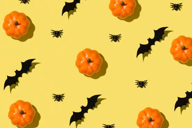 Photo of Happy Halloween concept. Overhead close up view photo of pattern of orange funny pumpkin spiders and bat isolated bright color yellow background