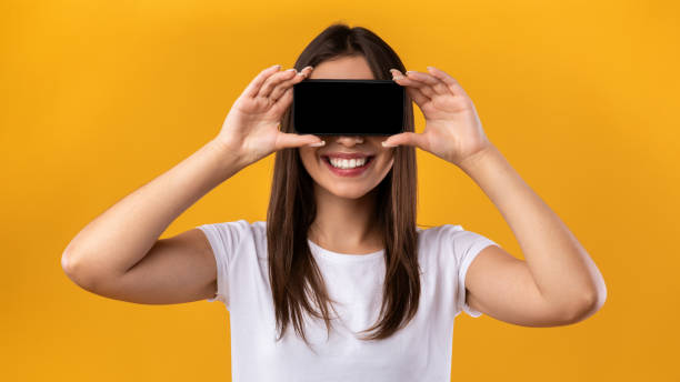donna che copre gli occhi con lo schermo nero vuoto dello smartphone - hiding internet multimedia people foto e immagini stock