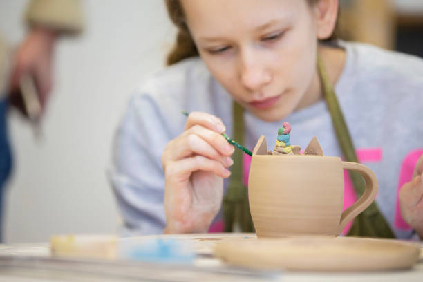 istock Clay modeling master class. A teenage girl sculpts a cup from clay. 1342037862