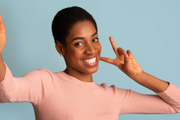 istock Cheerful Young Black Woman Taking Selfie And Gesturing Peace At Camera 1342038012