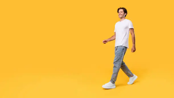 Photo of Young bearded man walking isolated on yellow background