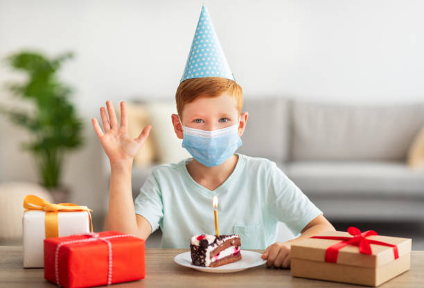 istock Boy in face mask and festive cap celebrating birthday 1342039408