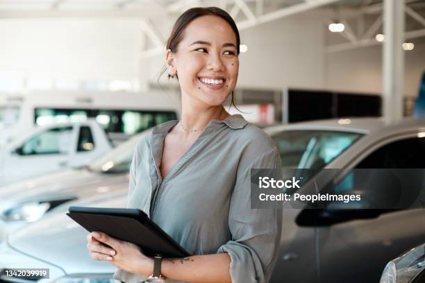 Shot Of A Woman Using Her Digital Tablet In A Car Dealership Stock Photo - Download Image Now