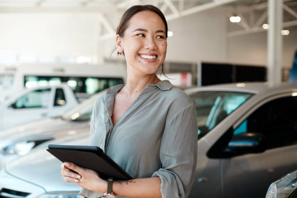 foto de uma mulher usando seu tablet digital em uma concessionária de carros - professional dealer - fotografias e filmes do acervo