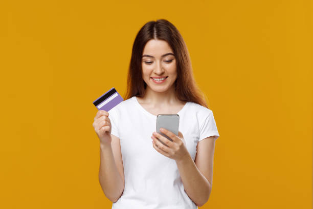 istock Smiling young woman using cellphone, holding credit card 1342042490