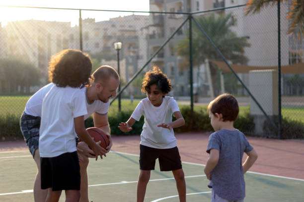 istock Different age kids playing basketball with their trainer. 1342043966