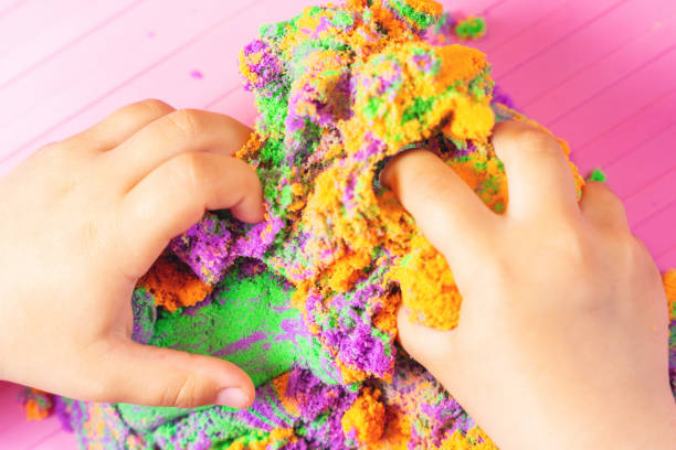 istock Hands of a child playing with multicolored kinetic sand 1342044237