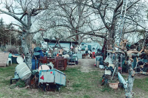 Photo of Hoarding disorder outdoors. Neglected allotment garden of people who suffers from compulsive hoarding, littered with trash and other items.