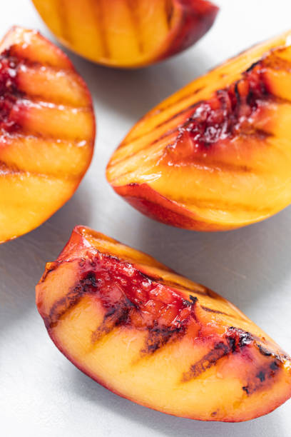 Juicy grilled nectarine quarters on light gray cutting board.