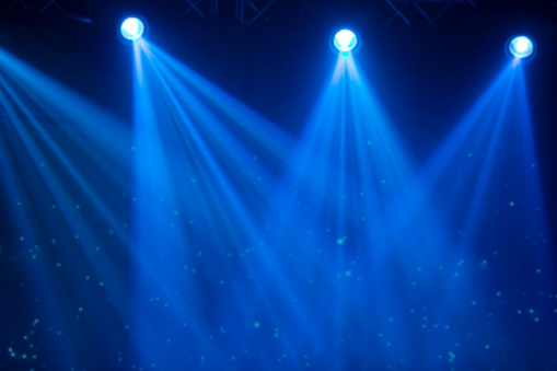 Blue rays of a stage spotlight on a dark background.