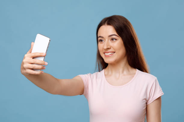 istock Attractive young lady taking selfie on blue studio background 1342045735
