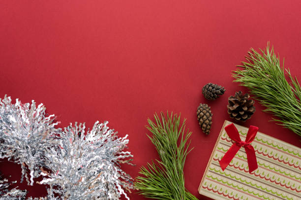 istock Christmas composition. A box with a gift and spruce branches on a red background. Spruce cones and Christmas decorations. Flat lay, top view, space for text 1342047309