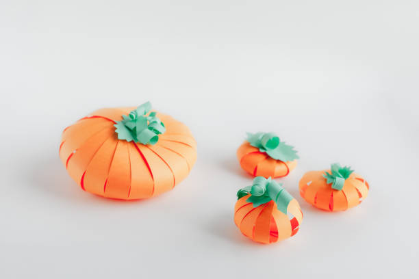 istock Some orange pumpkins made from paper on gray background 1342047578