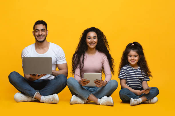 istock Technologies For Family. Arab Mom, Dad And Daughter Sitting With Different Gadgets 1342050495