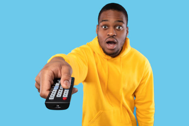 istock Shocked African Man Pointing Television Remote Controller Switching Channels, Studio 1342051514