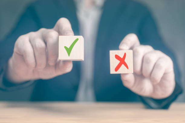 Accept and Decline. making a decision pros and cons. Choices Tick Yes No Choose Mark Decision. the businessman holds two cubes with signs for and against Accept and Decline. making decision pros and cons. Choices Tick Yes No Choose Mark Decision. businessman makes decision, Hands of businessman chooses checkmark and x sign symbol on wooden cube block pros and cons stock pictures, royalty-free photos & images