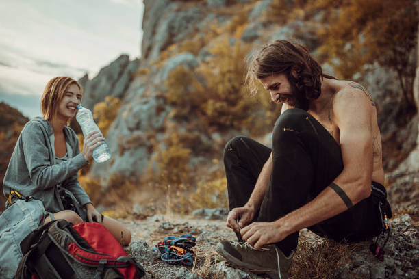 istock Man is tying shoe laces while woman is drinking water after rock climbing 1342052342