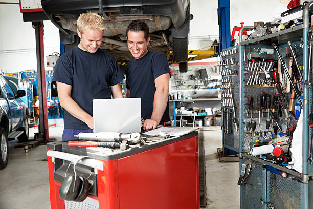 mechanika z laptopa w garażu - trainee auto repair shop computer manual worker zdjęcia i obrazy z banku zdjęć