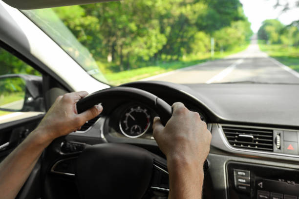 le mani maschili tengono il volante di un'auto durante la guida, vista interna. primo piano dell'interno dell'auto, cruscotto. - car steering wheel windshield speedometer foto e immagini stock