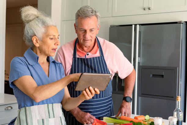 istock Happy caucasian senior couple standing in kitchen, using tablet and preparing meal together 1342053958