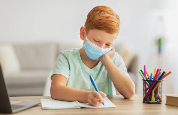 istock Preteen kid in face mask doing homework, copy space 1342053986