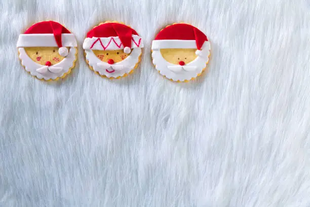 Christmas cookies with santa face on white fur background with copy space