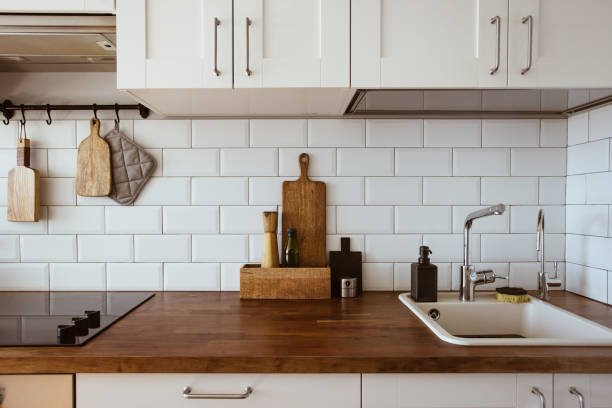 istock Kitchen brass utensils, chef accessories. Hanging kitchen with white tiles wall and wood tabletop.Kitchen background 1342055593