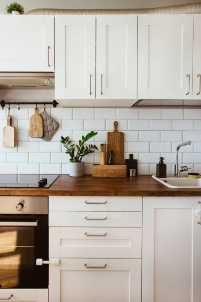 istock Kitchen brass utensils, chef accessories. Hanging kitchen with white tiles wall and wood tabletop.Green plant on kitchen background 1342056563