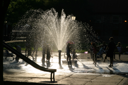 Kids playing in water at the playground in the Summer heat.