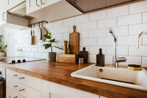 istock Kitchen brass utensils, chef accessories. Hanging kitchen with white tiles wall and wood tabletop.Green plant on kitchen background 1342057243