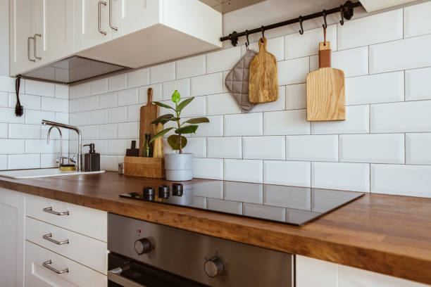 istock Kitchen brass utensils, chef accessories. Hanging kitchen with white tiles wall and wood tabletop.Green plant on kitchen background 1342057245