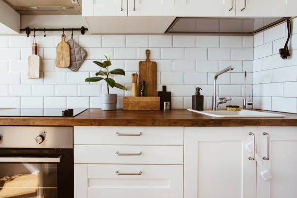 istock Kitchen brass utensils, chef accessories. Hanging kitchen with white tiles wall and wood tabletop.Green plant on kitchen background 1342057247