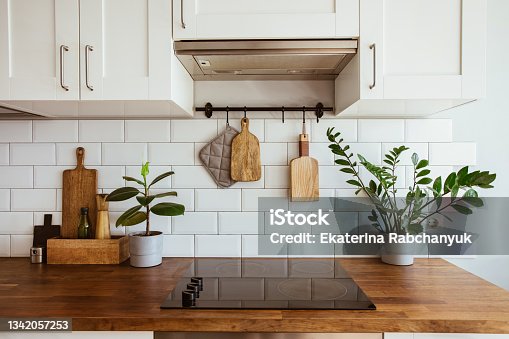 istock Kitchen brass utensils, chef accessories. Hanging kitchen with white tiles wall and wood tabletop.Green plant on kitchen background 1342057253