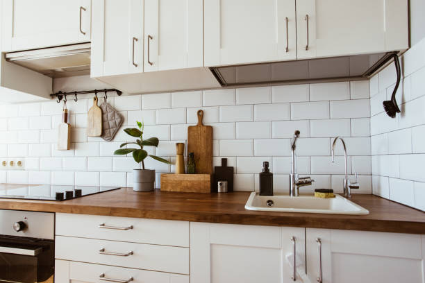 istock Kitchen brass utensils, chef accessories. Hanging kitchen with white tiles wall and wood tabletop.Green plant on kitchen background 1342057268