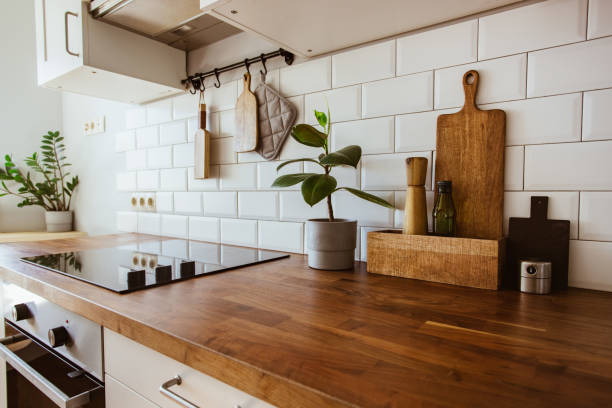 istock Kitchen brass utensils, chef accessories. Hanging kitchen with white tiles wall and wood tabletop.Green plant on kitchen background 1342057292