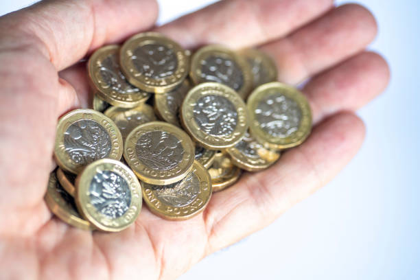 istock Man's hand holding a lot of one pound coins 1342061932