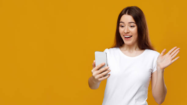 istock Excited young lady waving at mobile phone screen 1342062099