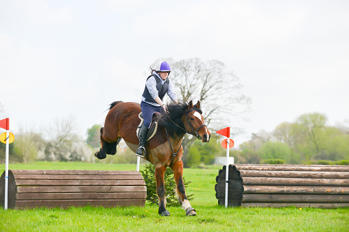 Up and over-young rider and her horse enjoying competing in cross country competition in the beautiful Shropshire countryside.