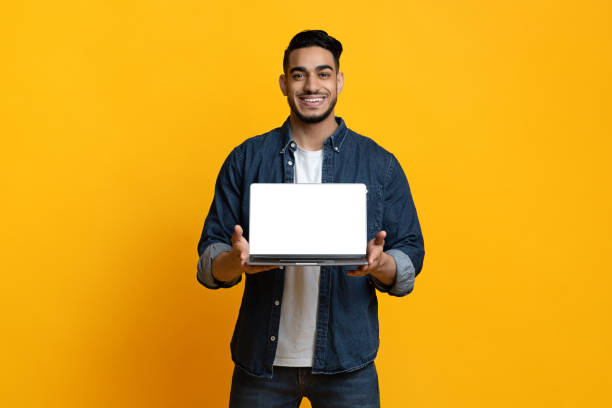 istock Cheerful arab guy showing laptop with blank screen 1342063062
