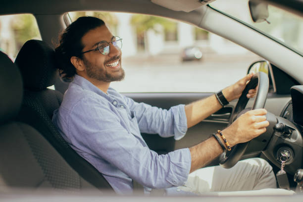 istock Handsome indian guy driving car, looking at rear view mirror 1342064303