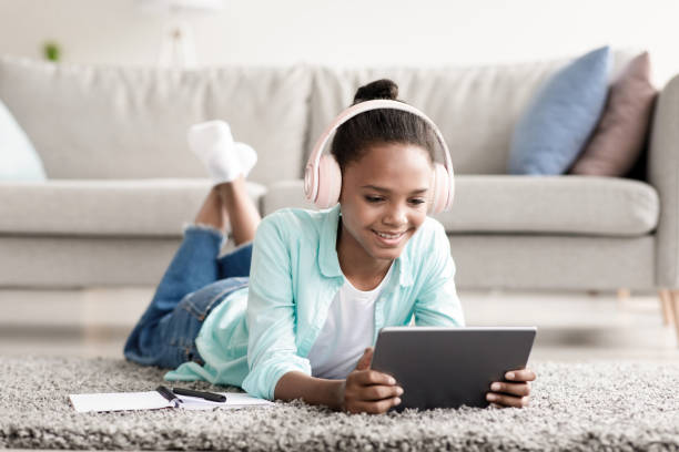 istock Little girl studying online using device at home. Beautiful young girl with headset learning remotely during covid-19 1342064867
