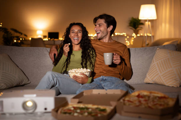 istock Cheerful Couple Using Home Cinema Projector Watching Comedy Movie Indoors 1342065623
